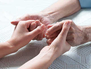 young nurse holds elderly persons hands